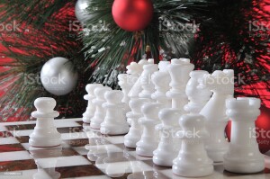 The initial position the white chess pieces with the first step of a pawn on the cell E4. The background is the Christmas tree, decorated with balloons.